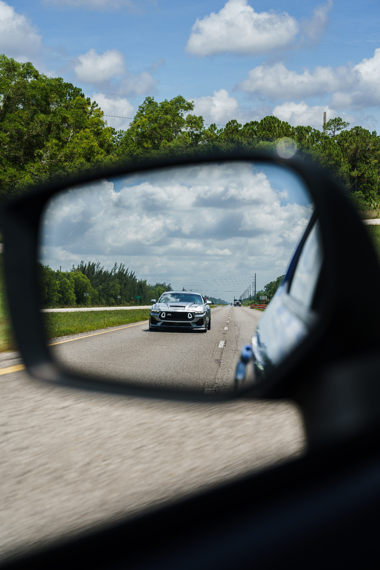 Silver Mustang RTR reflected in side mirror on the highway