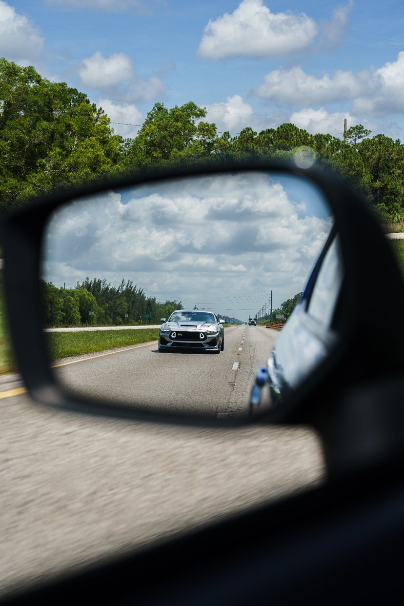 Silver Mustang RTR reflected in side mirror on the highway